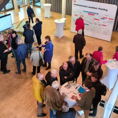 Mehrere Menschengruppen zwischen Plakaten auf einem Infomarkt
